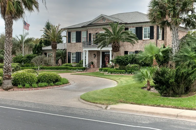 A brick home with a curved driveway and mature palms